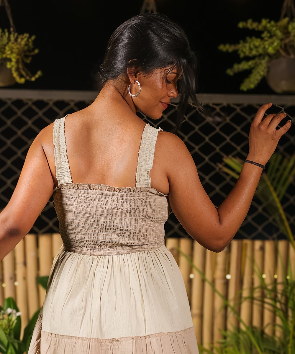 Back view of beige and off-white tiered maxi dress with tie straps and smocked elastic back.