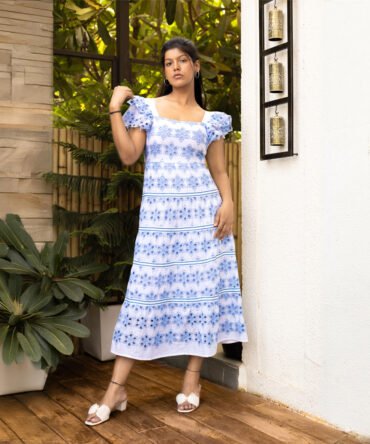 Model wearing blue and white cotton eyelet tiered dress with ruffle sleeves
