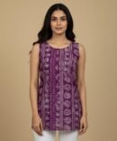 Model wearing purple batik print sleeveless cotton kurti with white pants, front view