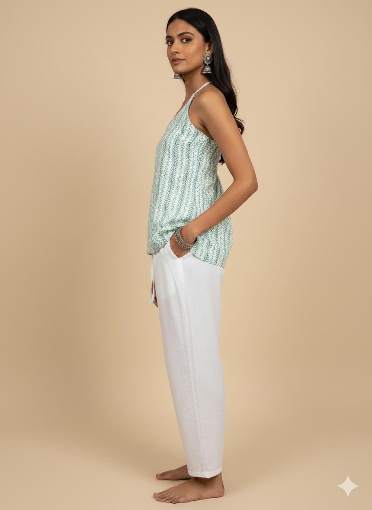 side pose of Model wearing green halter neck corset kurti with corset tie-back and halter straps, styled with white cotton pants — boho chic minimal summer outfit