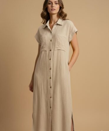 Woman wearing a biege cotton double gauze button-down dress styled for fall fashion, featuring short sleeves and a relaxed neutral chic look.